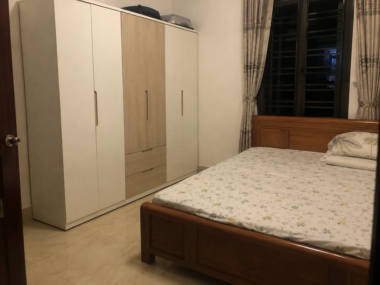 Tủ trắng ngà phối vân gỗ sáng dưới đèn phòng màu ấm