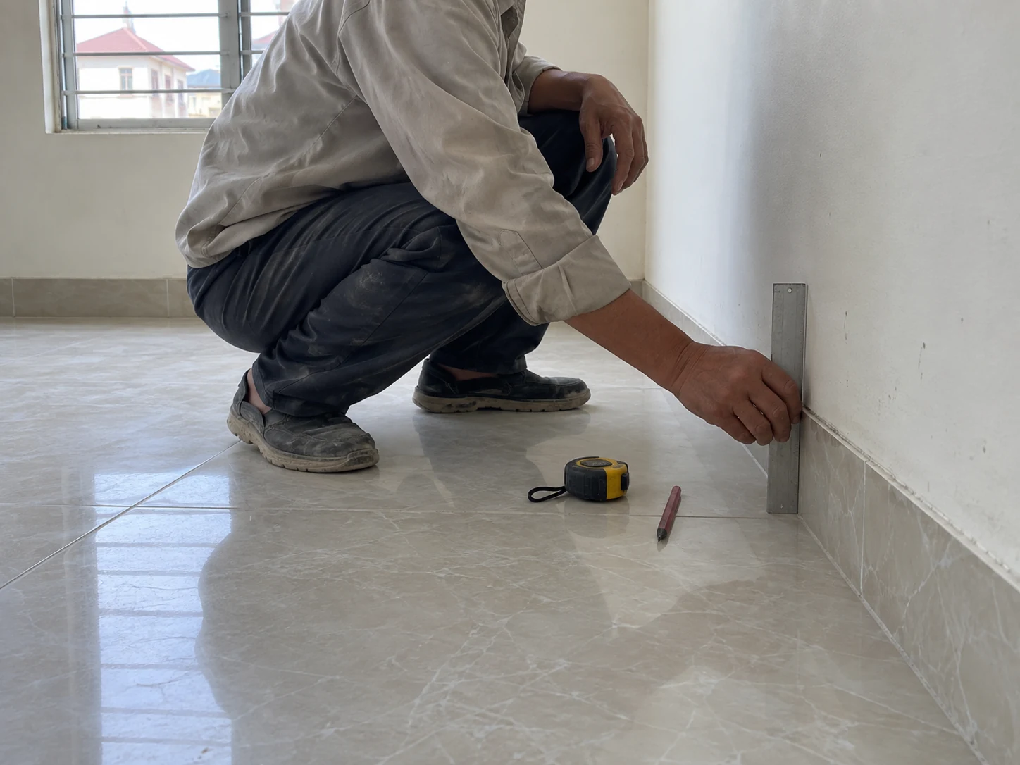 Người thợ kiểm tra chân tường và nền trước vị trí đặt tủ